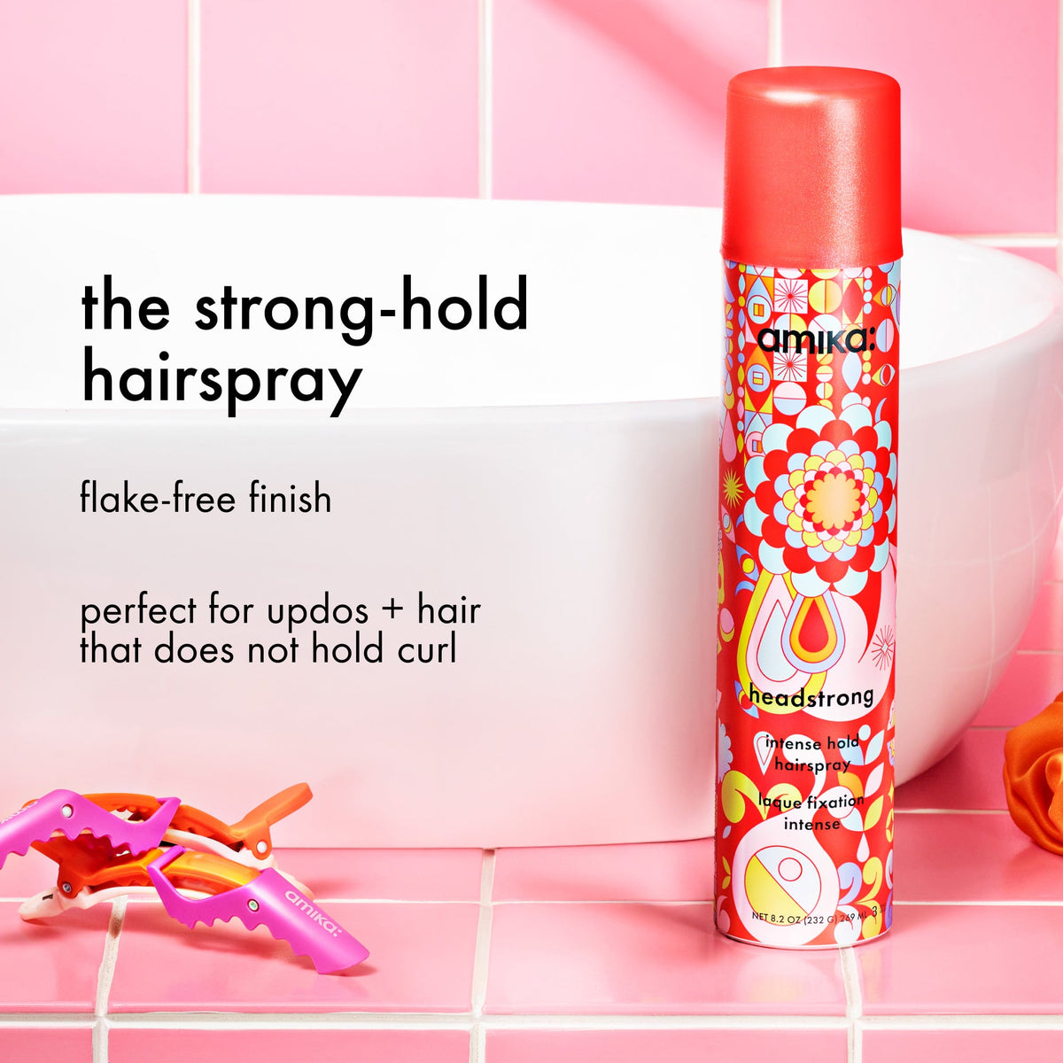 Amika headstrong hairspray bottle with text on a pink tiled background