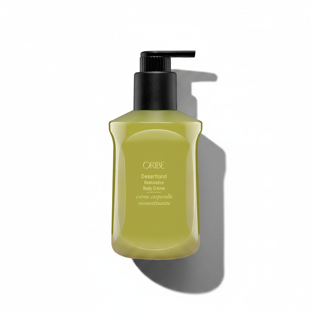 A pump bottle of Oribe Desertland Restorative Body Crème with a yellow-green label.