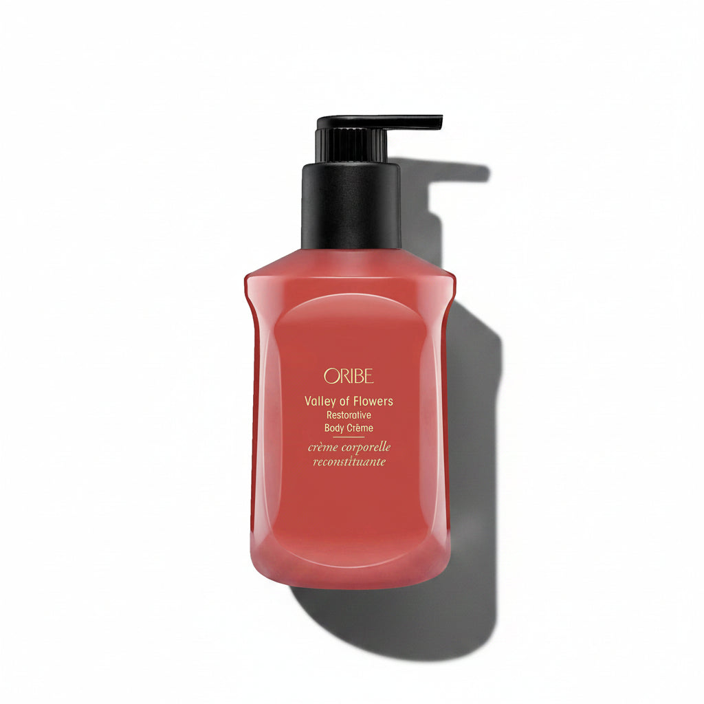 A pump bottle of Oribe Valley of Flowers Restorative Body Crème in a red shade.