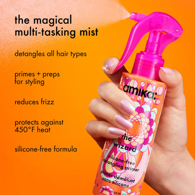 Image of a hand holding the Amika silicone-free detangling primer against an orange backgr