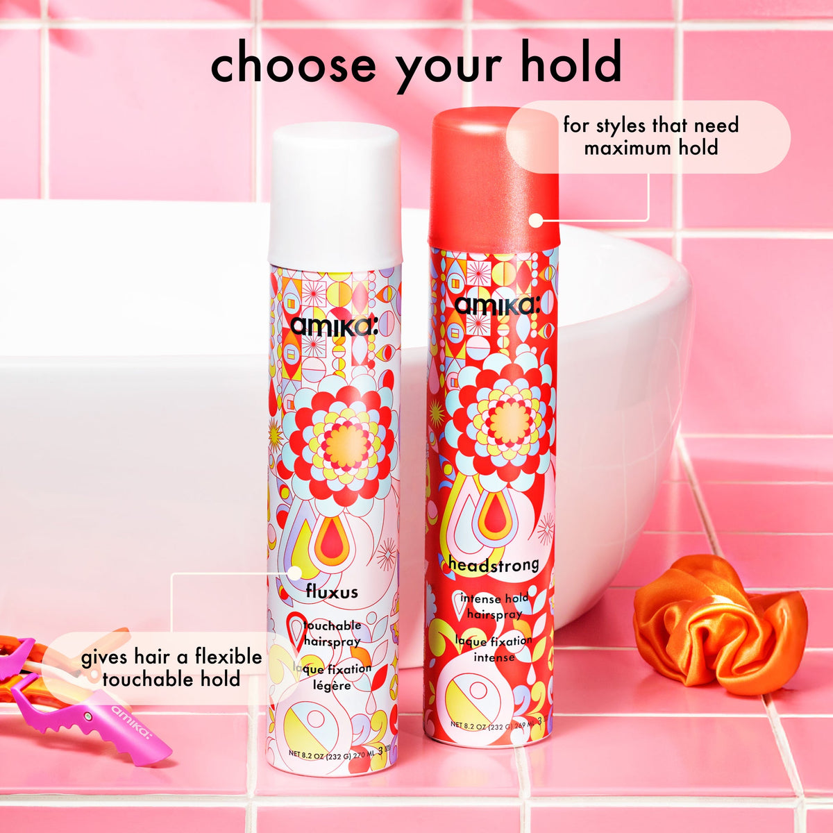 Two hair spray bottles with colorful designs on a pink tiled background.