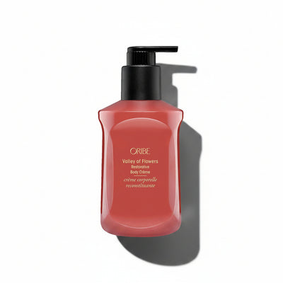 A pump bottle of Oribe Valley of Flowers Restorative Body Crème in a red shade.